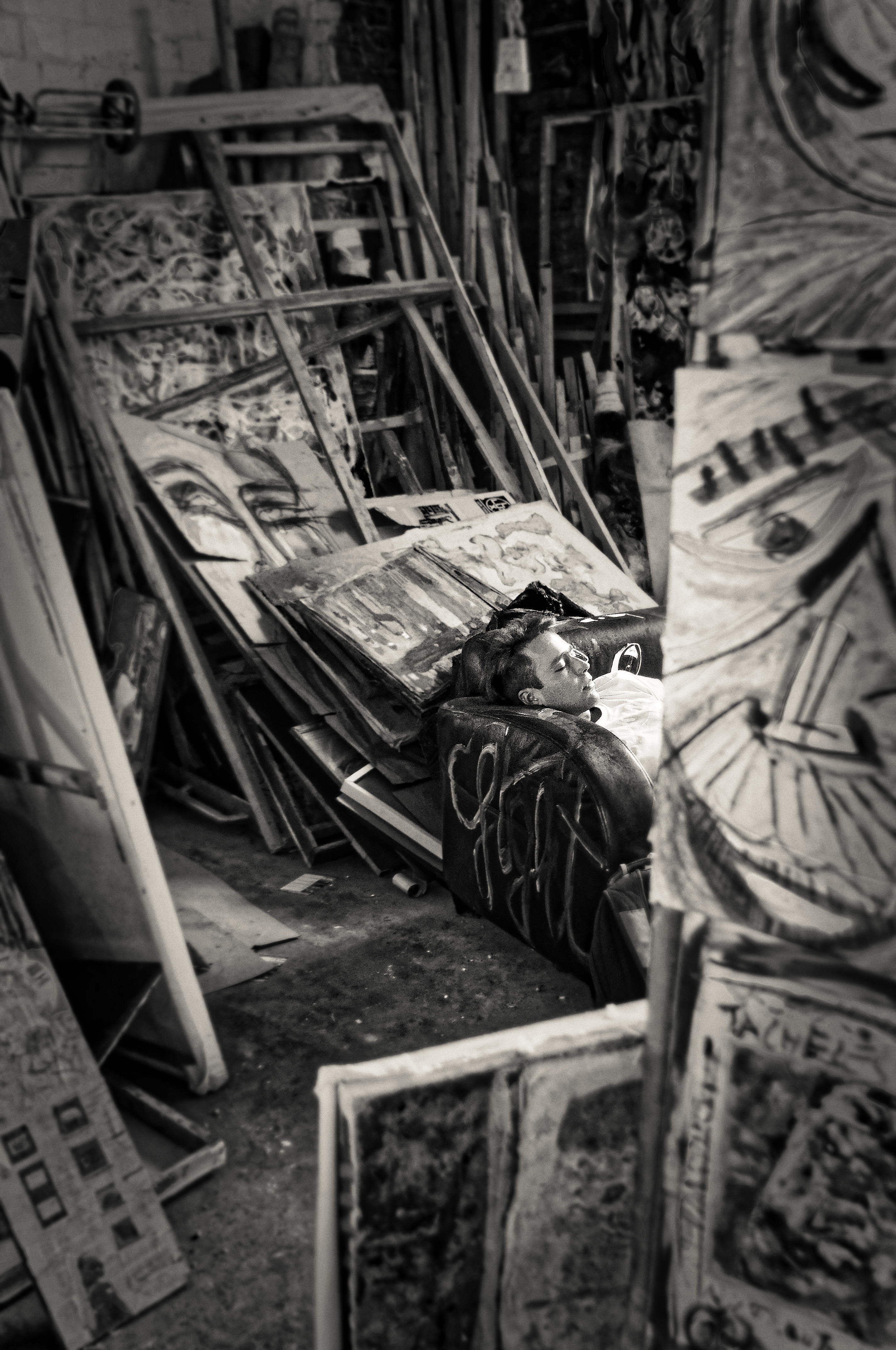 Person sleeping on a couch surrounded by paintings in a Berlin artist squat