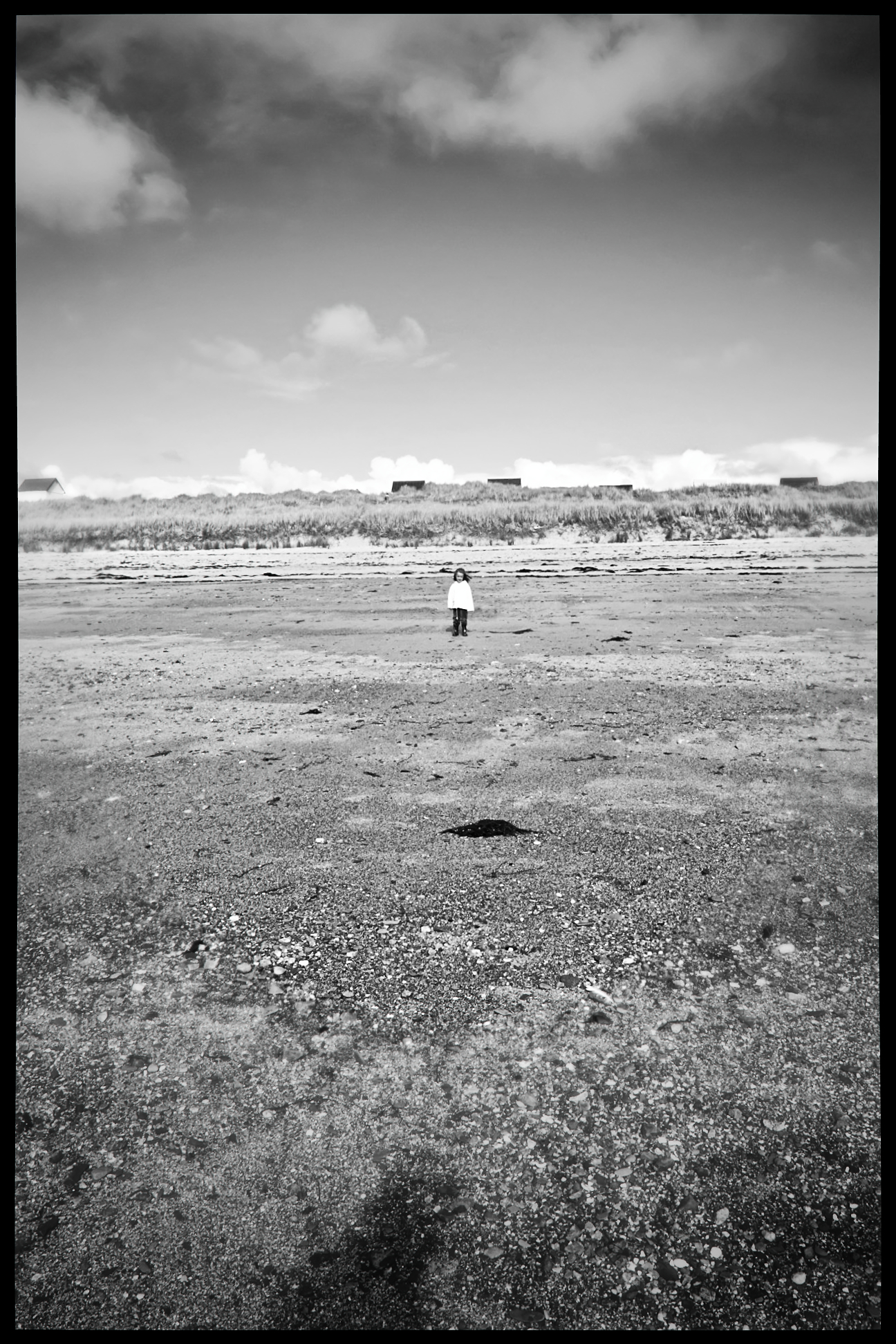 Lone figure standing on a vast empty beach